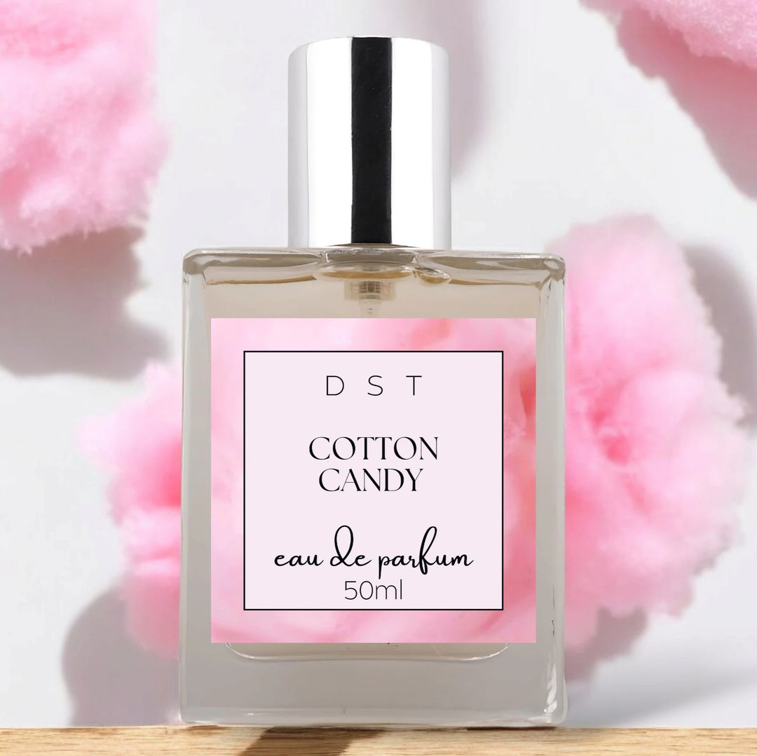 50ml bottle of Cotton Candy Eau de Parfum sitting on a wood counter top with pink cotton candy against a white background. 