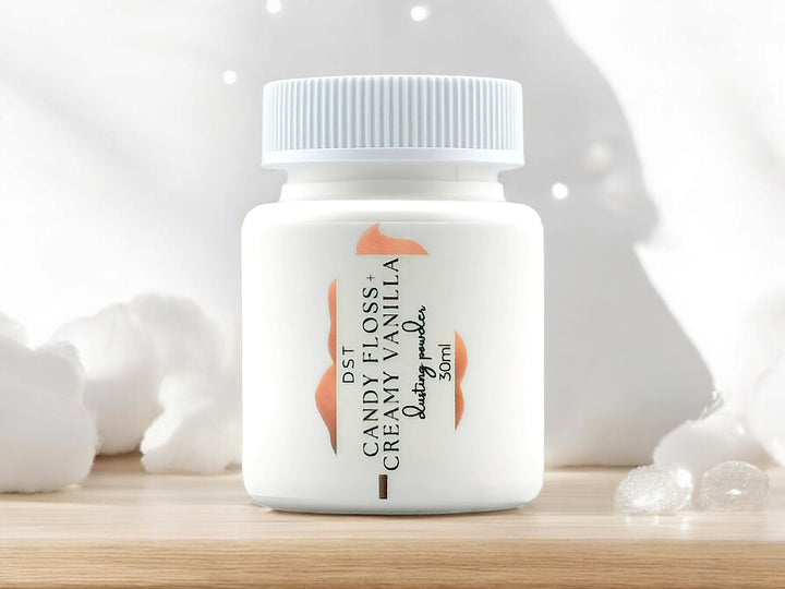 A 30ml bottle of Candy Floss and Creamy Vanilla scented body powder sitting on wood countertop with white cotton candy and twinkling lights in the white shadowy background.