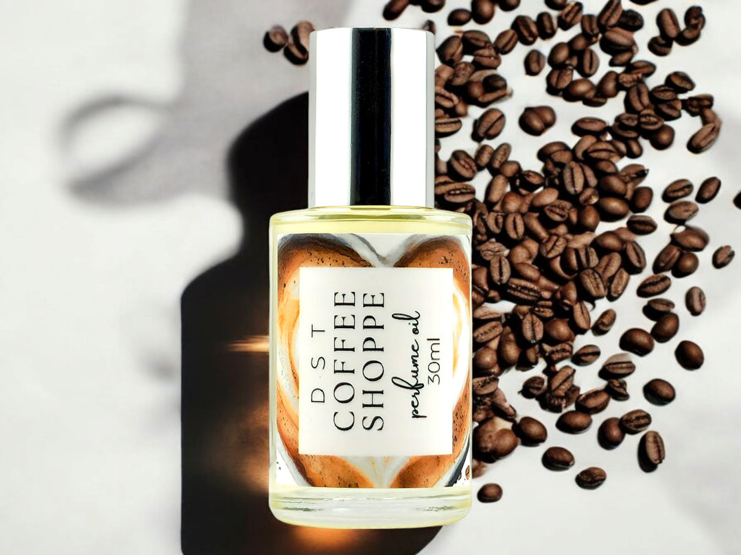 30ml bottle of Coffee Shoppe perfume oil against white shadowy background with scattered coffee beans.