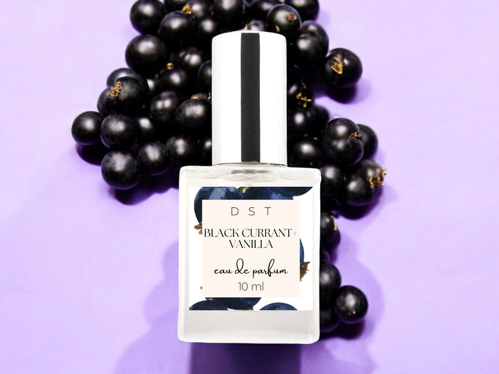 10ml bottle of black currant vanilla eau de parfum on purple background with black currants