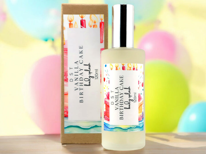 120ml bottle of Vanilla Birthday Cake body splash and the box it is packaged in with pink, yellow, and blue balloons against a pastel yellow background.