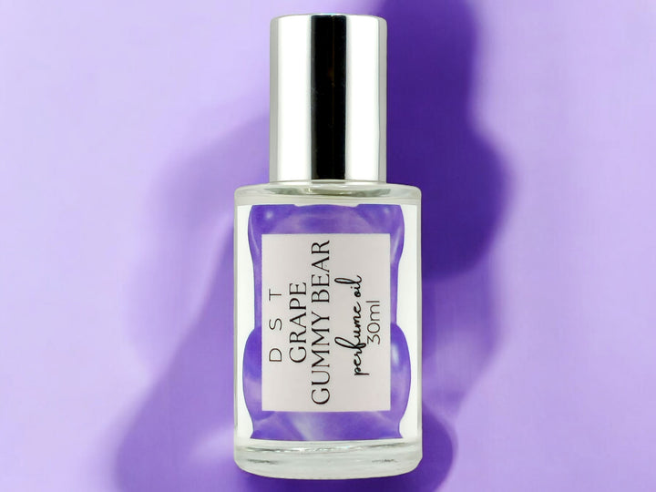 30ml bottle of Grape Gummy Bear perfume oil laying on pastel purple shadowy background.