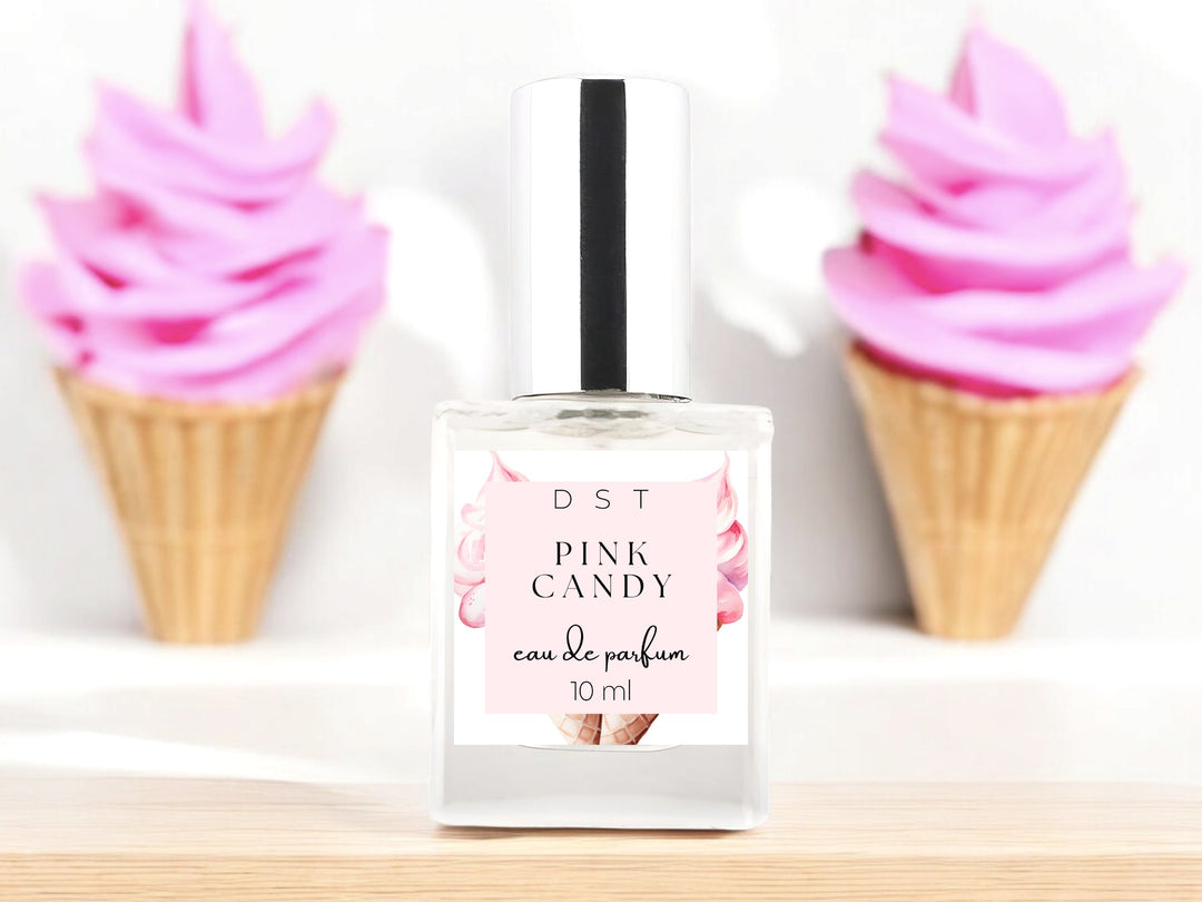 10ml bottle of Pink Candy Eau de parfum sitting on wood countertop with 2 waffle cones filled with bright pink ice cream in the white background.