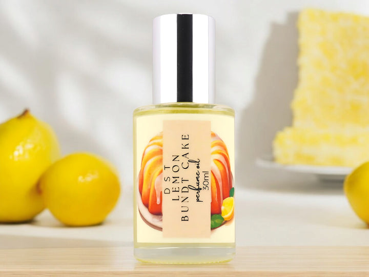 30ML bottle of lemon bundt cake perfume oil sitting on a wood countertop with lemons and lemon cake against a white background.