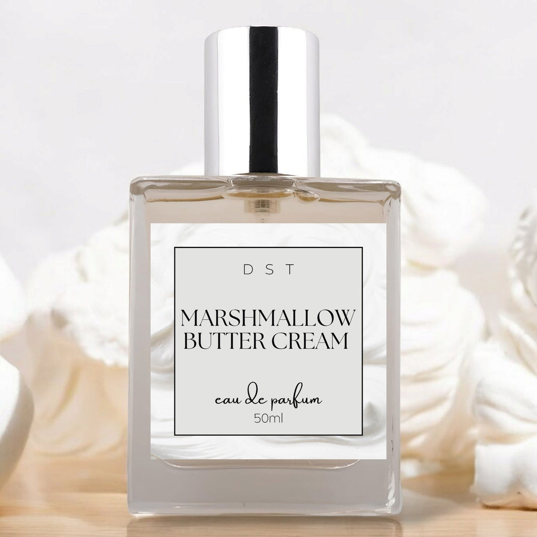 50ml bottle of Marshmallow Butter Cream Eau de Parfum sitting on wood counter top with white background and dollops of white frosting surrounding the bottle.