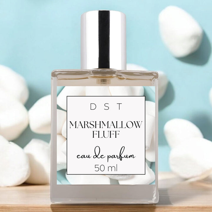 50ml bottle of Marshmallow Fluff Eau de Parfum sitting on wood counter top with light blue background and white marshmallows. 