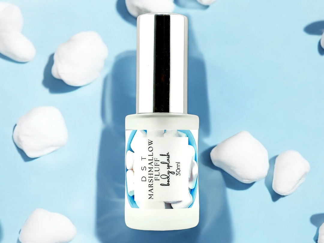 1oz bottle of Marshmallow Fluff Body Splash set on light blue background and white fluffy marshmallows. 