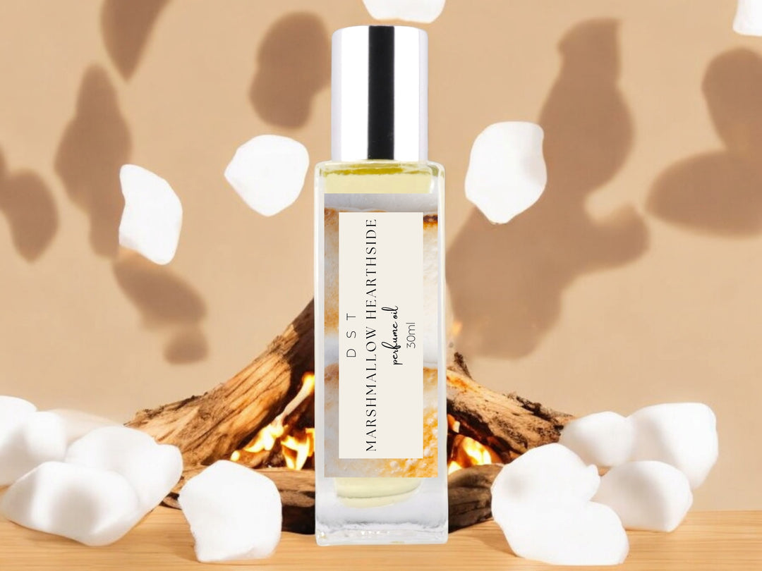 30ml bottle of Marshmallow Hearthside perfume oil sitting in front of a campfire and white puffy marshmallows against a shadowy tan background.