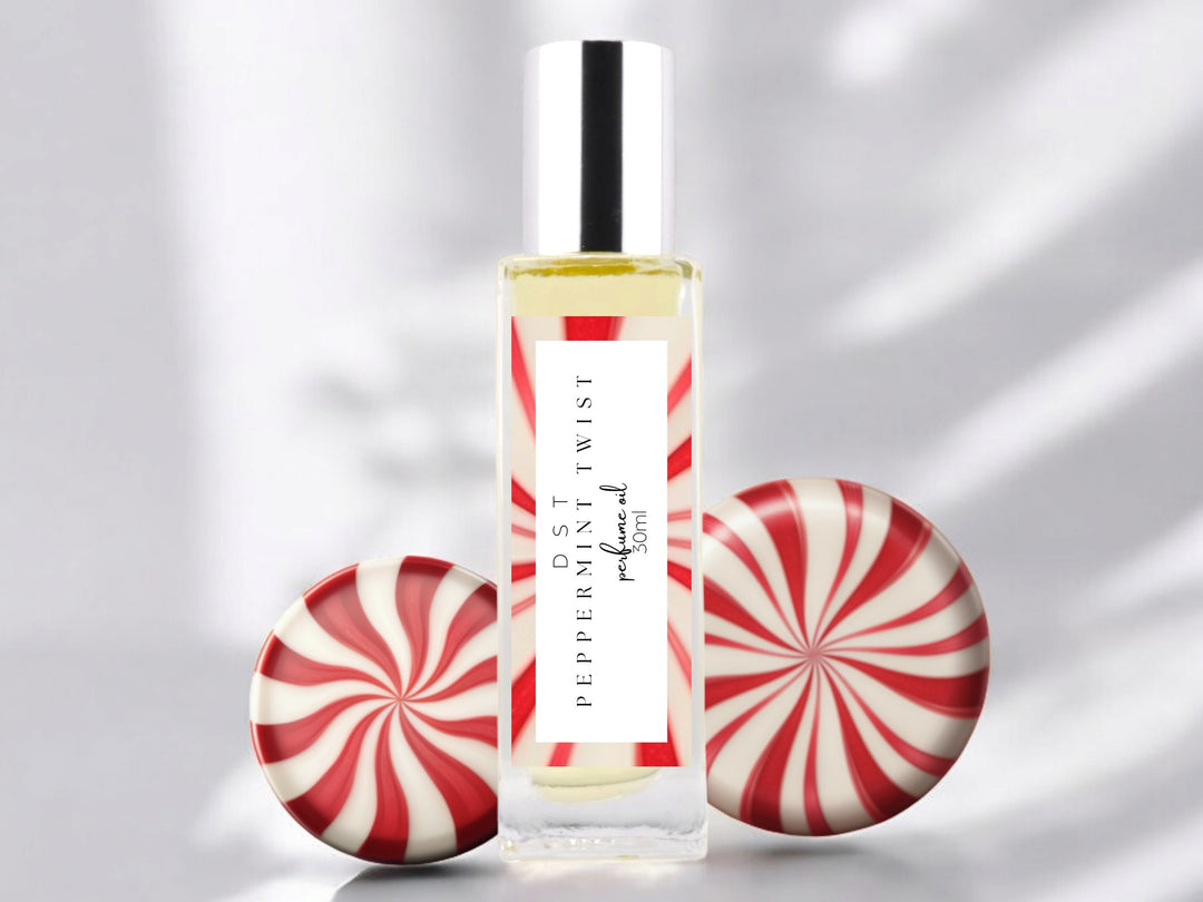 30ml bottle of Peppermint Twist perfume oil sitting on white surface with 2 peppermint swirl candies set against white background.