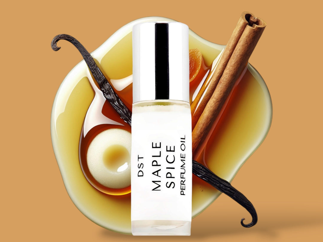 5ML bottle of Maple Spice perfume oil sitting in front of a large puddle of maple syrup, with Vanilla creme,  and vanilla bean and cinnamon stick on top against a tan background.