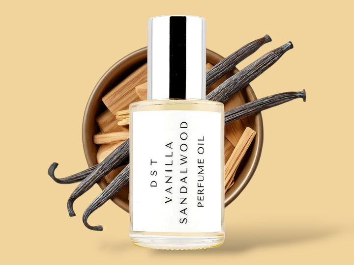 30ML bottle of Vanilla Sandalwood perfume oil sitting in front of a large white bowl filled with sandalwood and vanilla beans against a light brown background. 