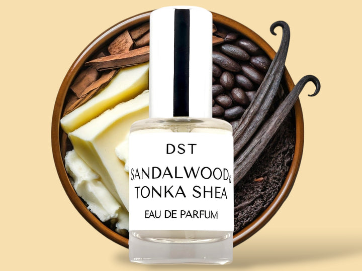 10ML bottle of Sandalwood and Tonka Shea Parfum sitting in front of a large wooded bowl filled with shea butter, tonka beans, Sandalwood, and long vanilla beans, against a tan background. 