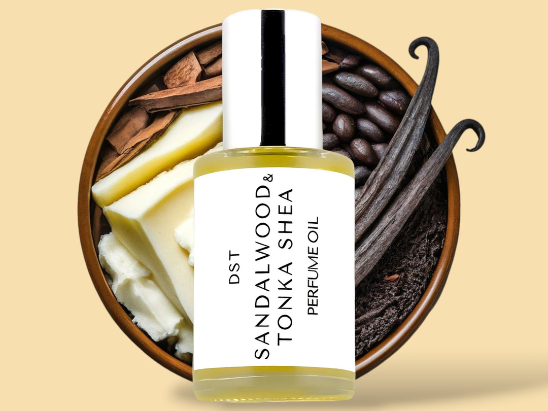 30ml bottle of Sandalwood and Tonka Shea scented perfume oil sitting in front of a wooden bowl filled with shea butter, Sandalwood, tonka and vanilla beans against a cream background. 