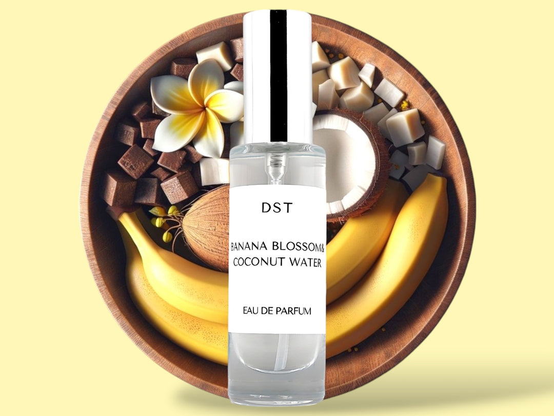 30ML bottle of Banana Blossom and Coconut Water Eau de Parfum sitting in front of a large wooden bowl filled with bananas, tiare flowers, and coconut halves, against a light yellow background. 