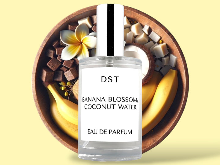 100ML bottle of Banana Blossom and Coconut Water Eau de Parfum sitting in front of a large wooden bowl filled with bananas, tiare flowers, and coconut halves, against a light yellow background. 