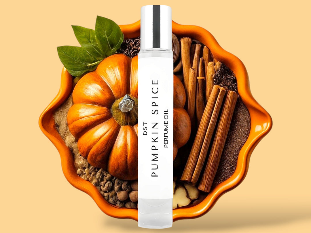 10ml bottle of Pumpkin Spice perfume oil sitting in front of an orange bowl filled with pumpkins, cinnamon sticks, and spices, against a light orange background. 