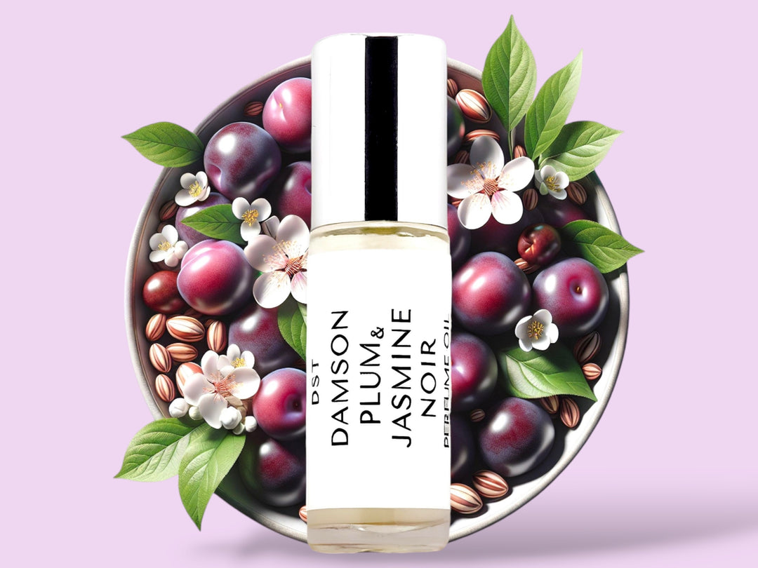 5ML bottle of Damson Plum and Jasmine Noir Perfume Oil sitting in front of a white bowl filled with purple plums and jasmine flowers against a pastel purple background. 