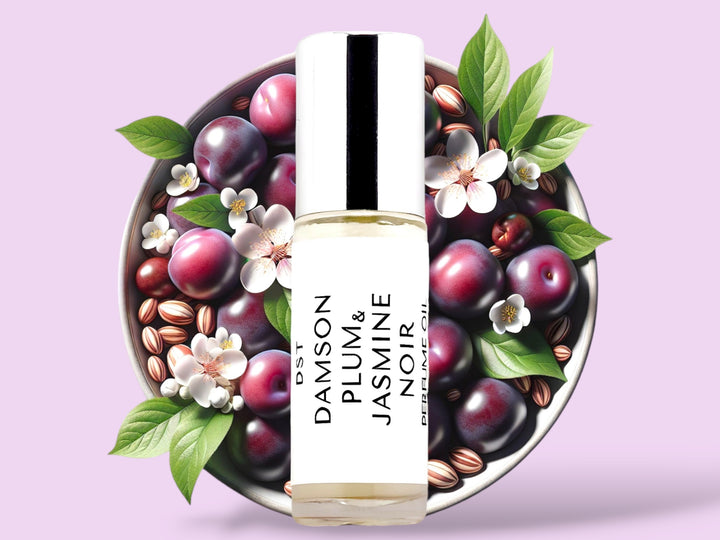 5ML bottle of Damson Plum and Jasmine Noir Perfume Oil sitting in front of a white bowl filled with purple plums and jasmine flowers against a pastel purple background. 