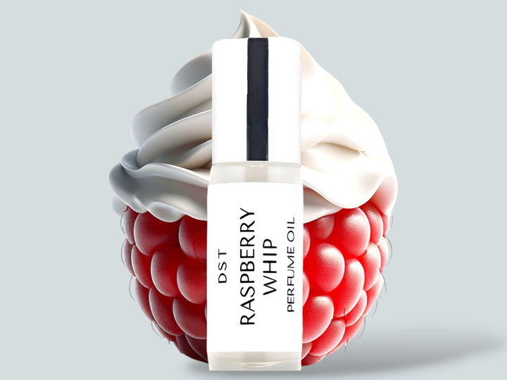 5ML bottle of Raspberry Whip perfume oil sitting in front of a large Raspberry topped with whipped cream against a light grey background. 