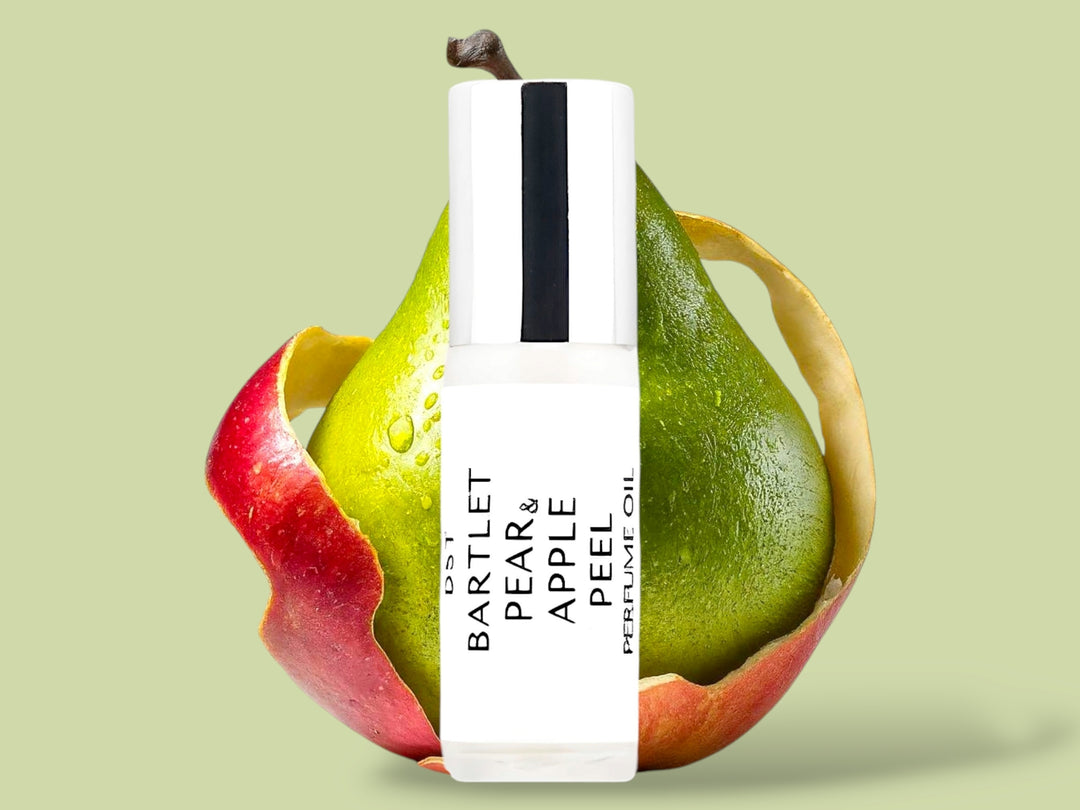 5ml bottle of Bartlet Pear and Apple Peel perfume oil sitting in front of a green pear that is wrapped in  red Apple Peel on a light green background.