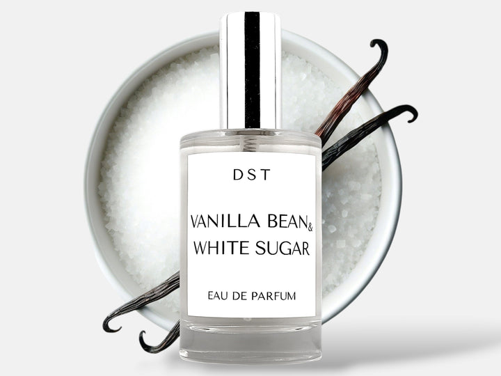 100ml bottle of Vanilla Bean and White Sugar Parfum sitting in front of a large white bowl filled with white sugar with 2 long vanilla beans on top that are lying on top against a white background. 