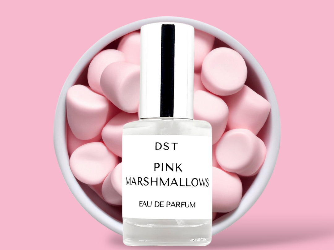 10ML bottle of Pink Marshmallows Eau de Parfum sitting in front of a large white bowl filled with fluffy pink marshmallows against a pastel pink background. 