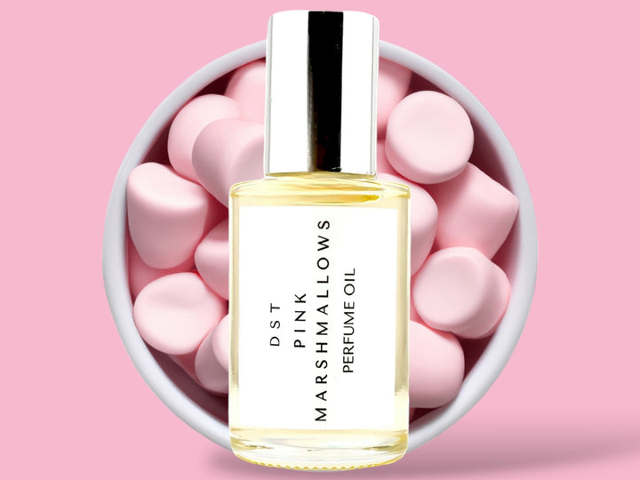 30ml bottle of Pink Marshmallows Perfume Oil sitting in front  of a large white bowl filled with Pink Marshmallows against a pink background. 