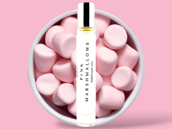 10ml bottle of Pink Marshmallows Perfume Oil sitting in front  of a large white bowl filled with Pink Marshmallows against a pink background. 