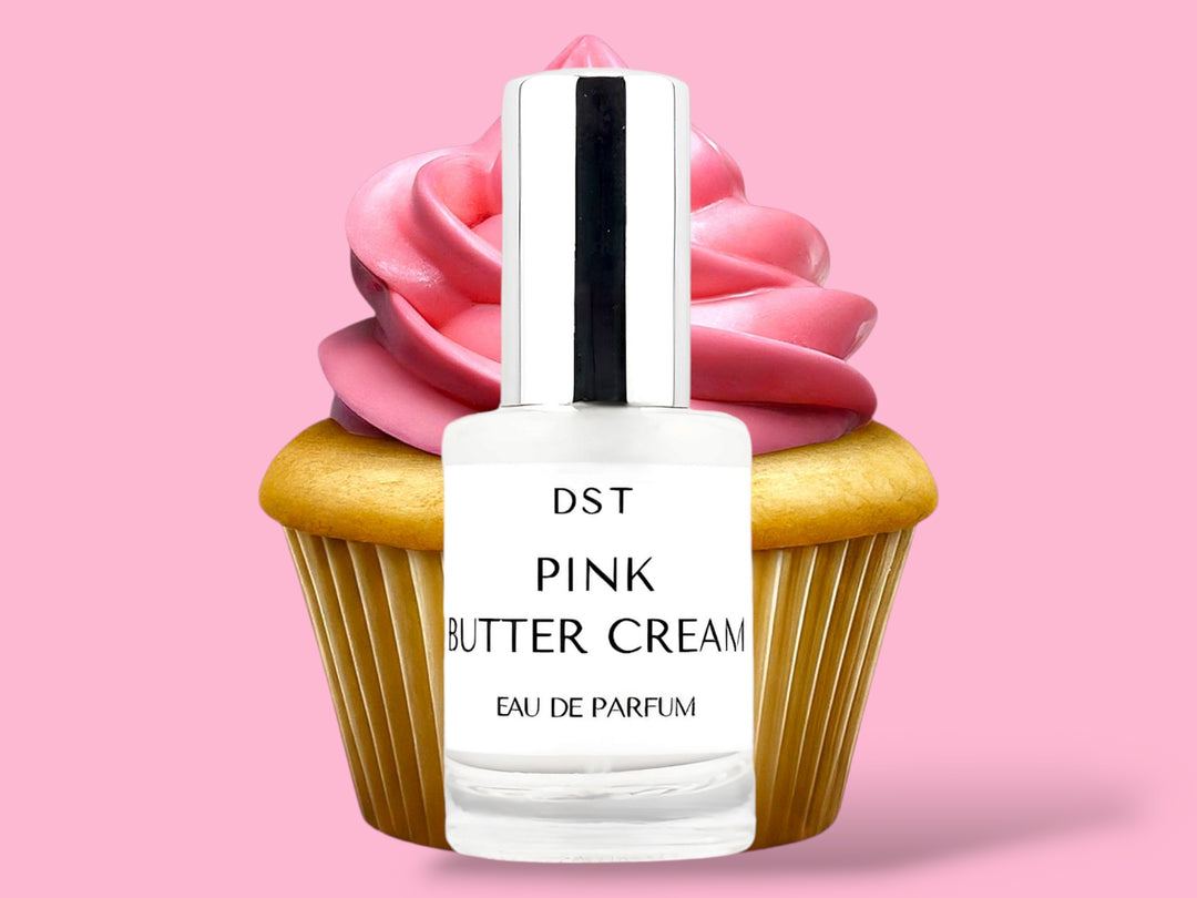 10ml bottle of Pink Butter Cream Parfum sitting in front of a large vanilla cupcake with bright pink frosting against a pink background. 