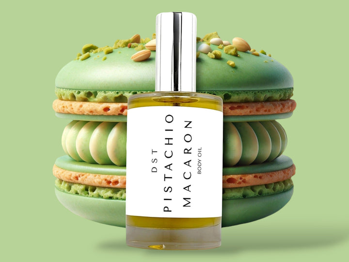 100ml bottle of Pistachio Macaron body oil sitting in front of a large green Pistachio Macaron against a green background. 