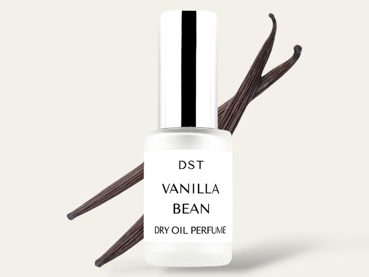 30ML bottle of Vanilla Bean Dry Oil Perfume Spray sitting in front of a large vanilla bean against a white background. 