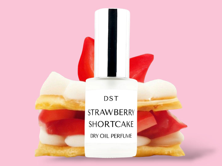 30ML bottle of Strawberry shortcake Dry Oil Perfume Spray sitting in front of a large Strawberry Shortcake against a pink background. 