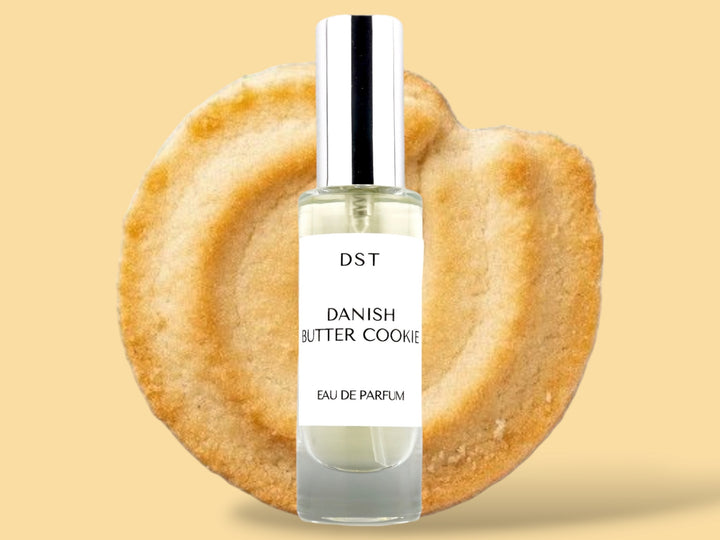 30ML bottle of Danish Butter Cookie Eau de Parfum sitting in front of a large Butter cookie against a pastel yelloe background. 