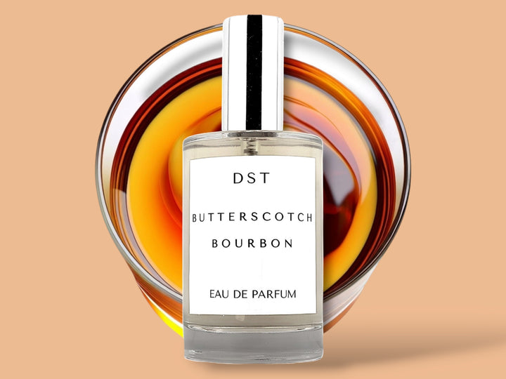 100ML bottle of Butterscotch and Bourbon Eau de Parfum sitting in front of a large glass of bourbon against a pastel orange background. 