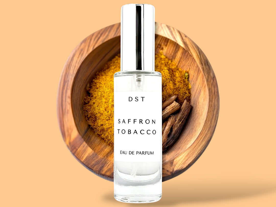 30 ML bottle of saffron tobacco Eau de parfum sitting in front of a wooden bowl filled with saffron against an orange background.