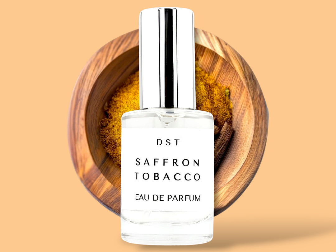 10 ML bottle of saffron tobacco Eau de parfum sitting in front of a wooden bowl filled with saffron against an orange background.