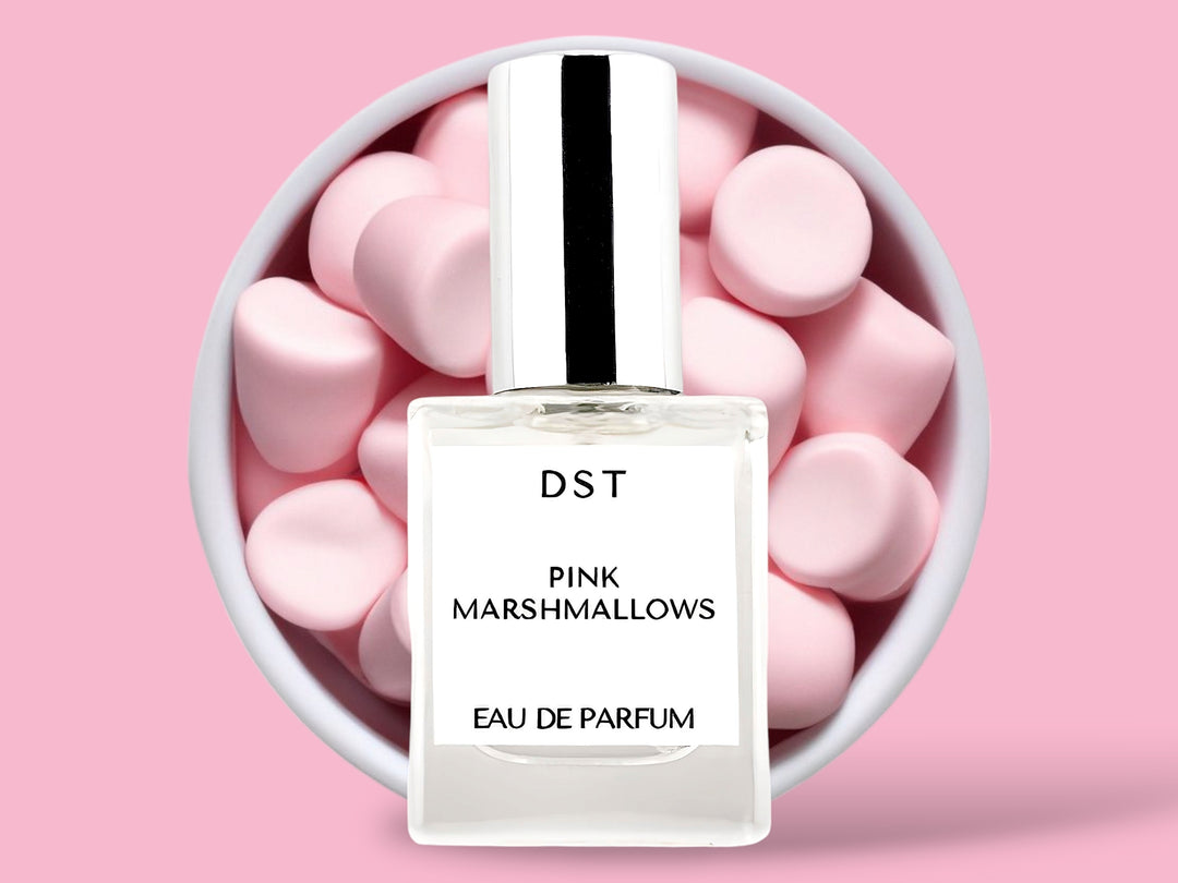 10ML bottle of Pink Marshmallows Eau de Parfum sitting in front of a large white bowl filled with fluffy pink marshmallows against a pastel pink background. 