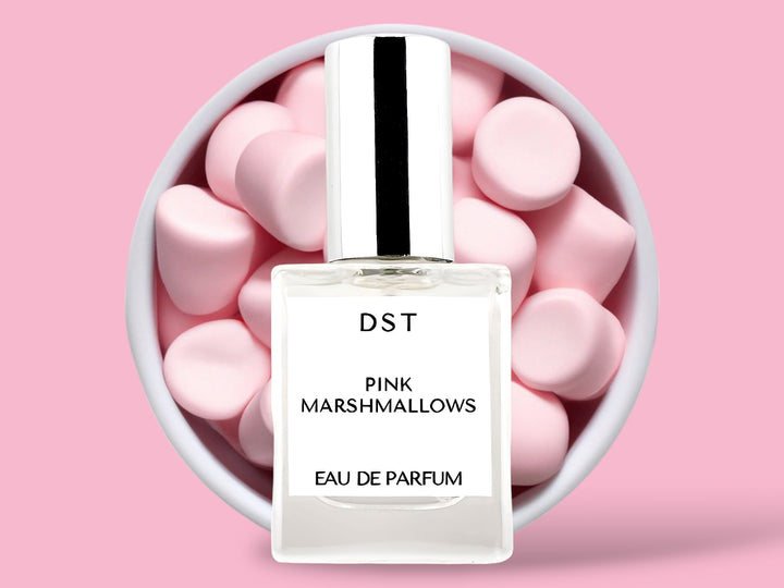 10ML bottle of Pink Marshmallows Eau de Parfum sitting in front of a large white bowl filled with fluffy pink marshmallows against a pastel pink background. 