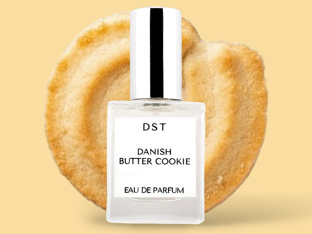 10ML bottle of Danish Butter Cookie Eau de Parfum sitting in front of a large Butter cookie against a pastel yelloe background. 