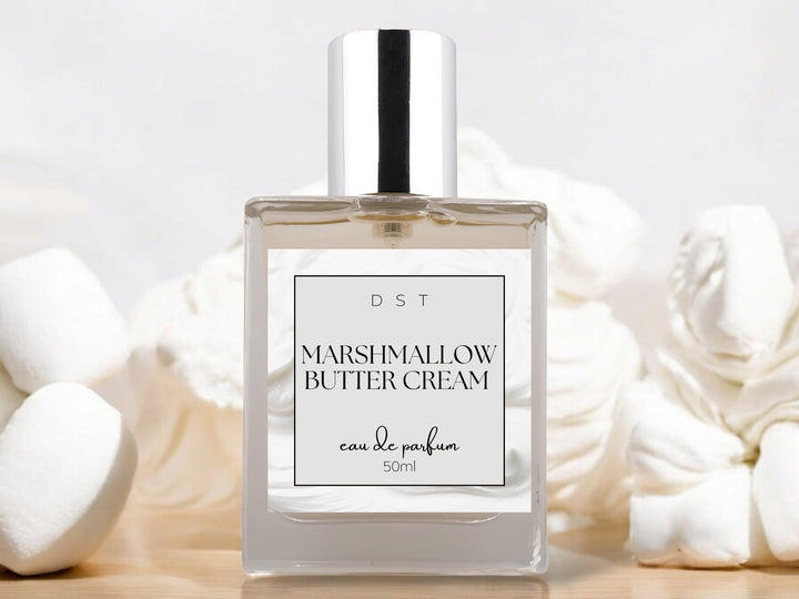 50ml bottle of Marshmallow Butter Cream Eau de Parfum sitting on wood counter top with white background and dollops of white frosting surrounding the bottle.