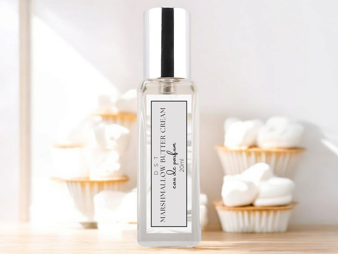 20ml bottle of Marshmallow Butter Cream Eau de Parfum sitting on wood counter top with white background and vanilla frosted cupcakes surrounding the bottle.