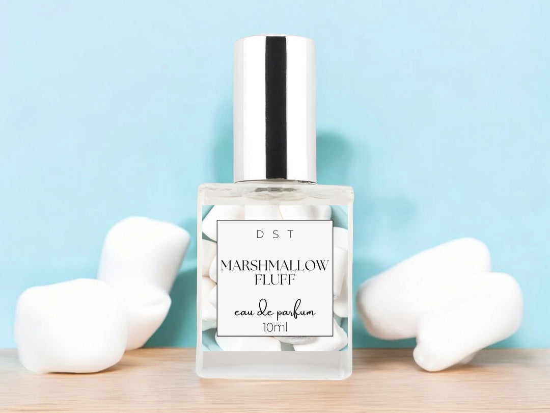 10ml bottle of Marshmallow Fluff Eau de Parfum sitting on wood counter top with light blue background and white marshmallows. 