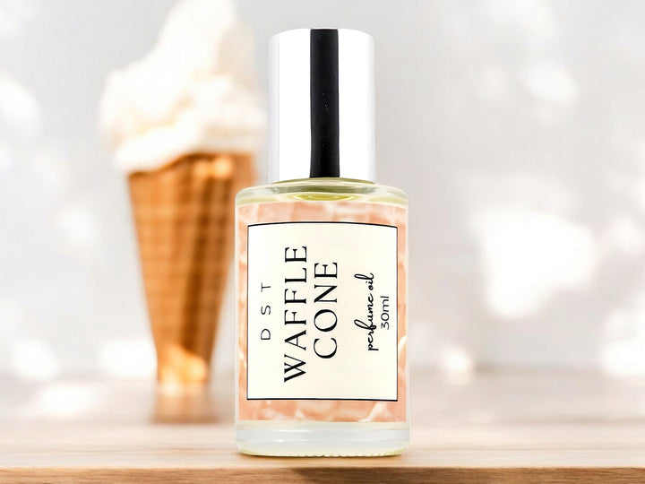 30ml bottle of waffle cone perfume oil sitting on wood counter top with white background and waffle cone filled with vanilla ice cream.