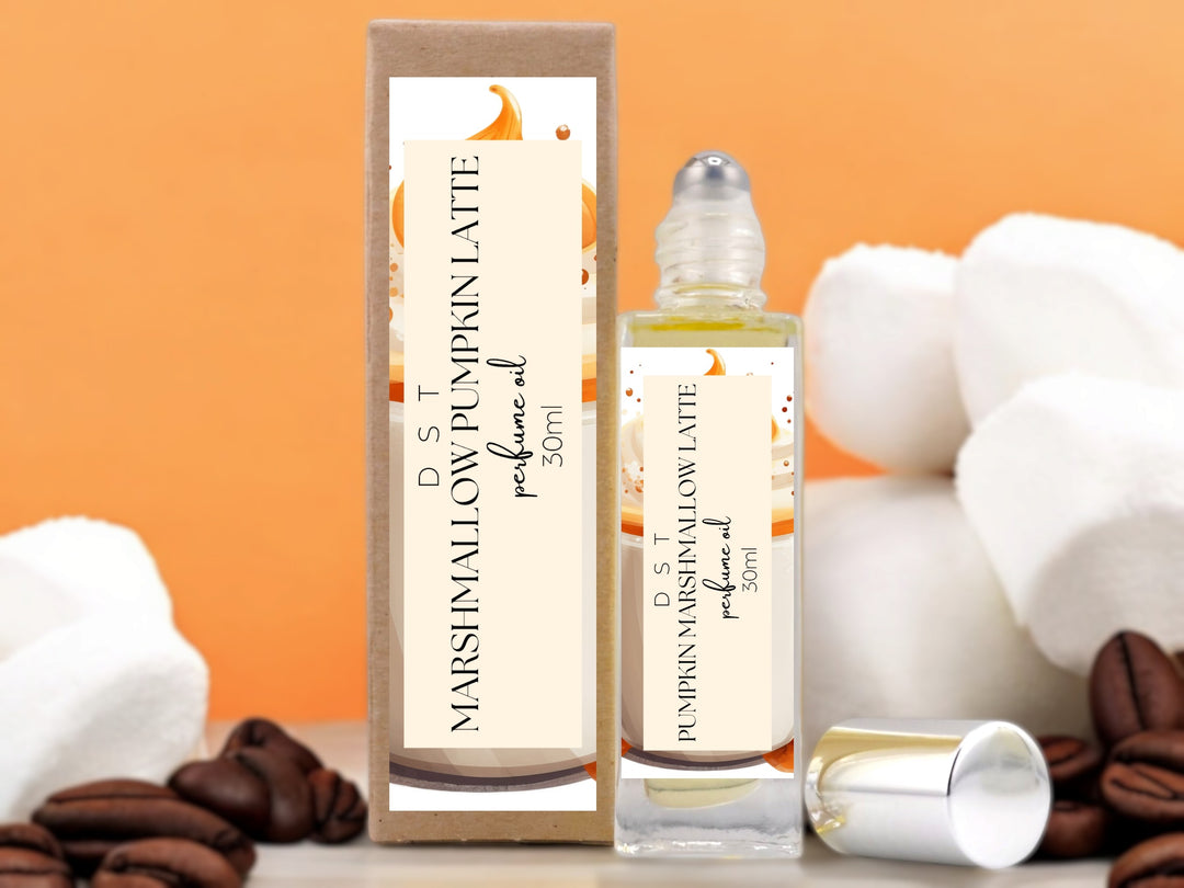 30ml bottle of marshmallow pumpkin latte perfume oil and the box it is packaged in on orange background with white marshmallows and coffee beans