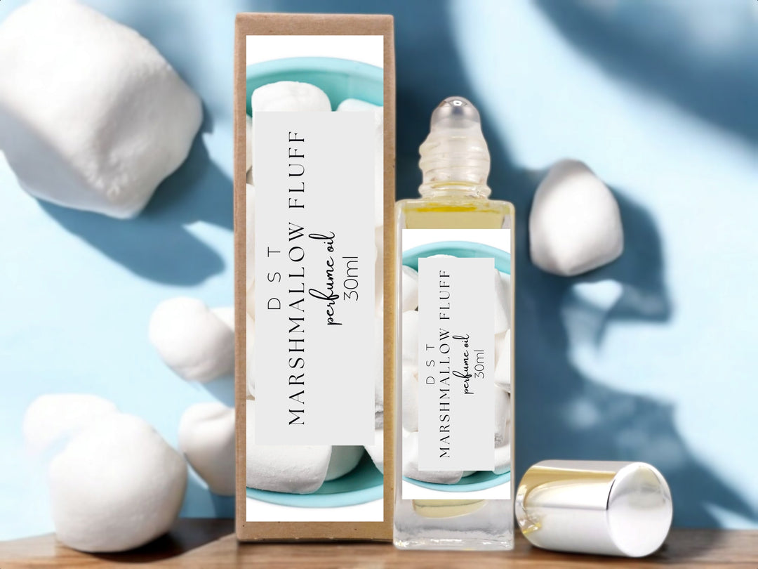 30ml bottle of Marshmallow Fluff scented Perfume Oil and the box it is packaged in surrounded by light blue background and puffy white marshmallows. 