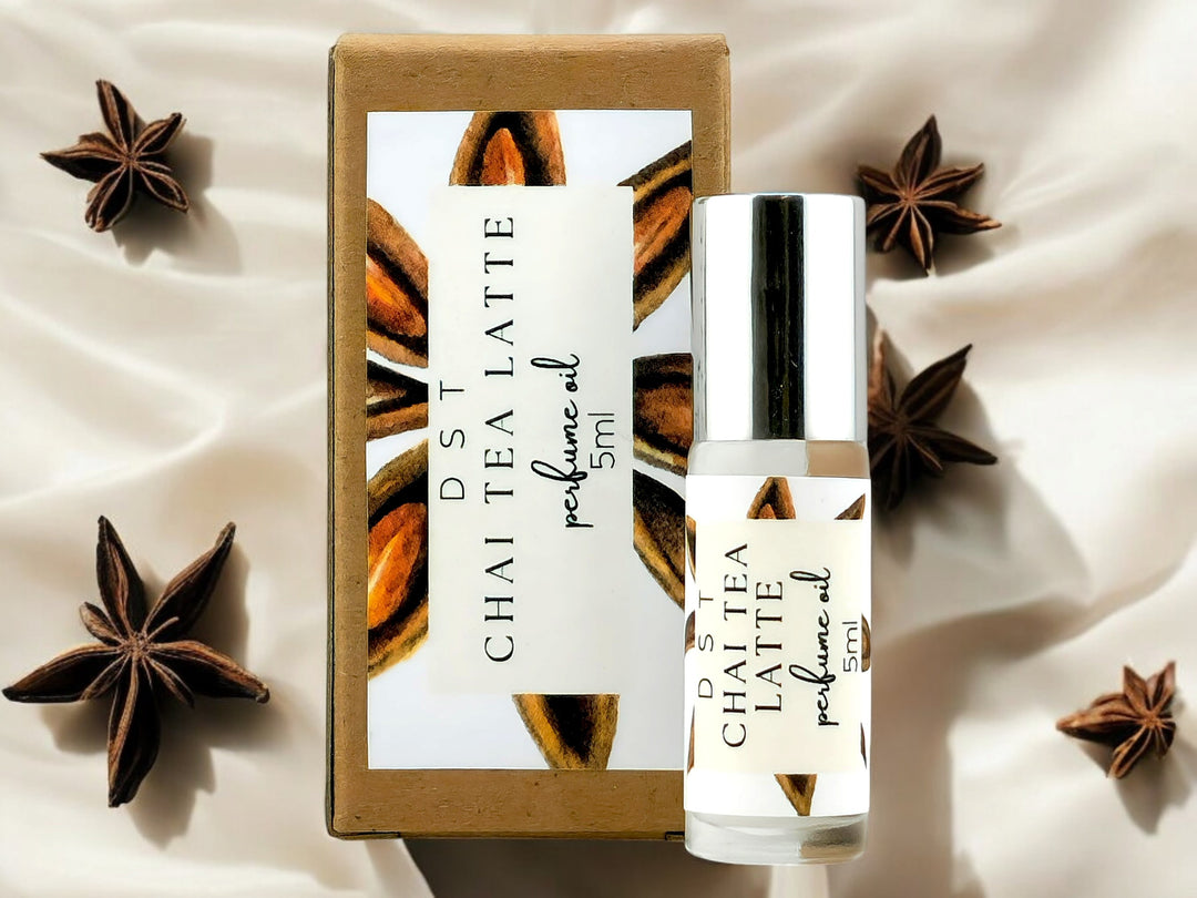 5ml bottle of Chai Tea Latte Perfume Oil and the box it is packaged in surrounded by star anise against an ivory colored background.