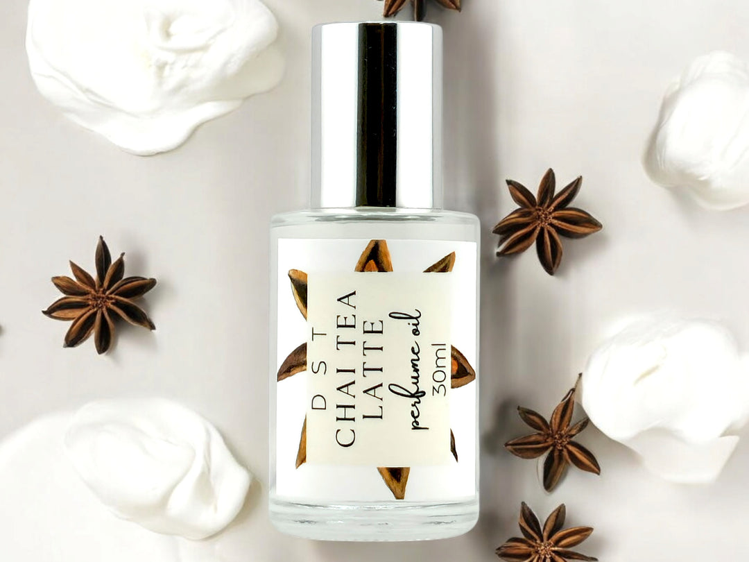 30ml bottle of Chai Tea Latte Perfume Oil surrounded by star anise and dollops of frothy cream against an ivory colored background.