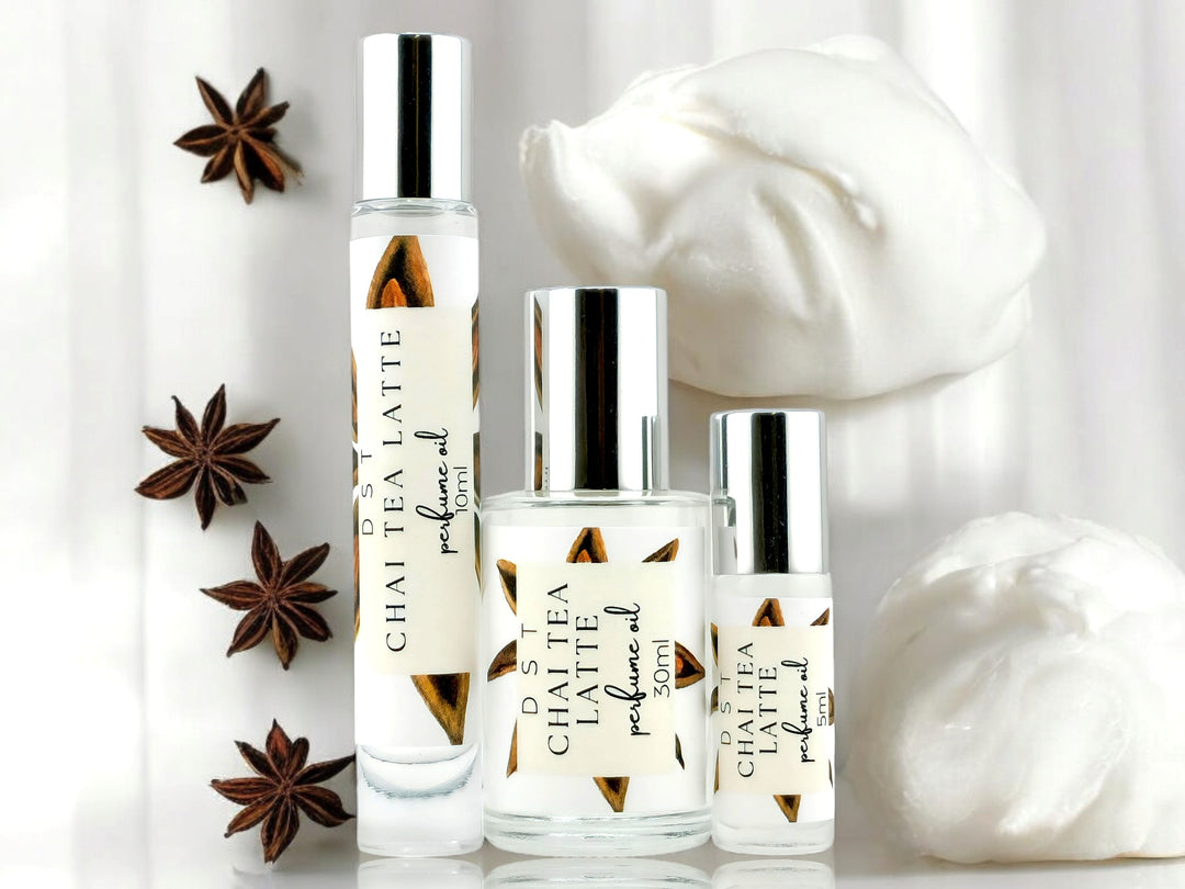 5, 10, and 30ml bottles of Chai Tea Latte Perfume Oil surrounded by star anise and dollops of frothy cream against an ivory colored background.