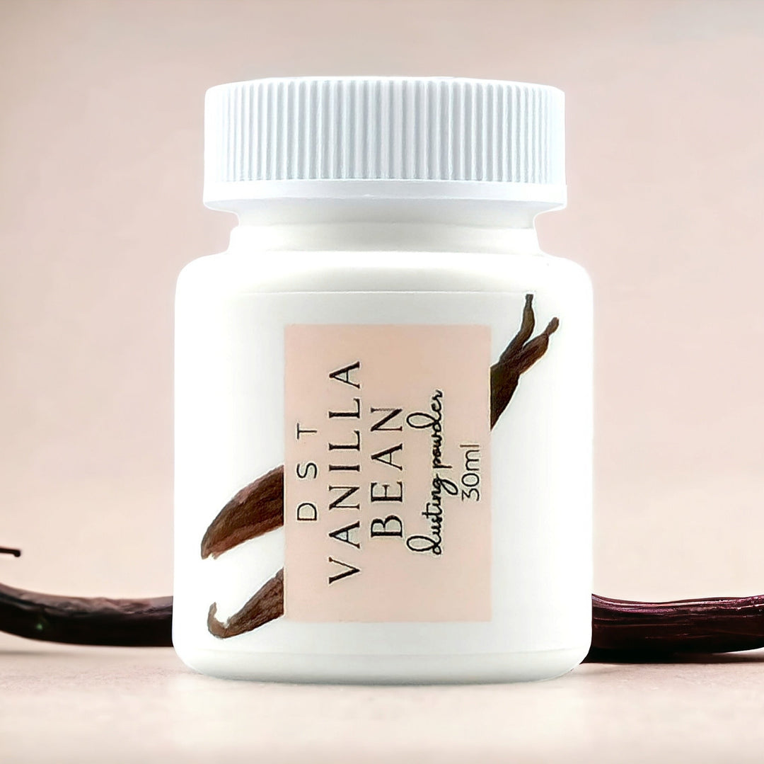 30ml bottle of Vanilla Bean scent body powder against a tan background with vanilla beans. 