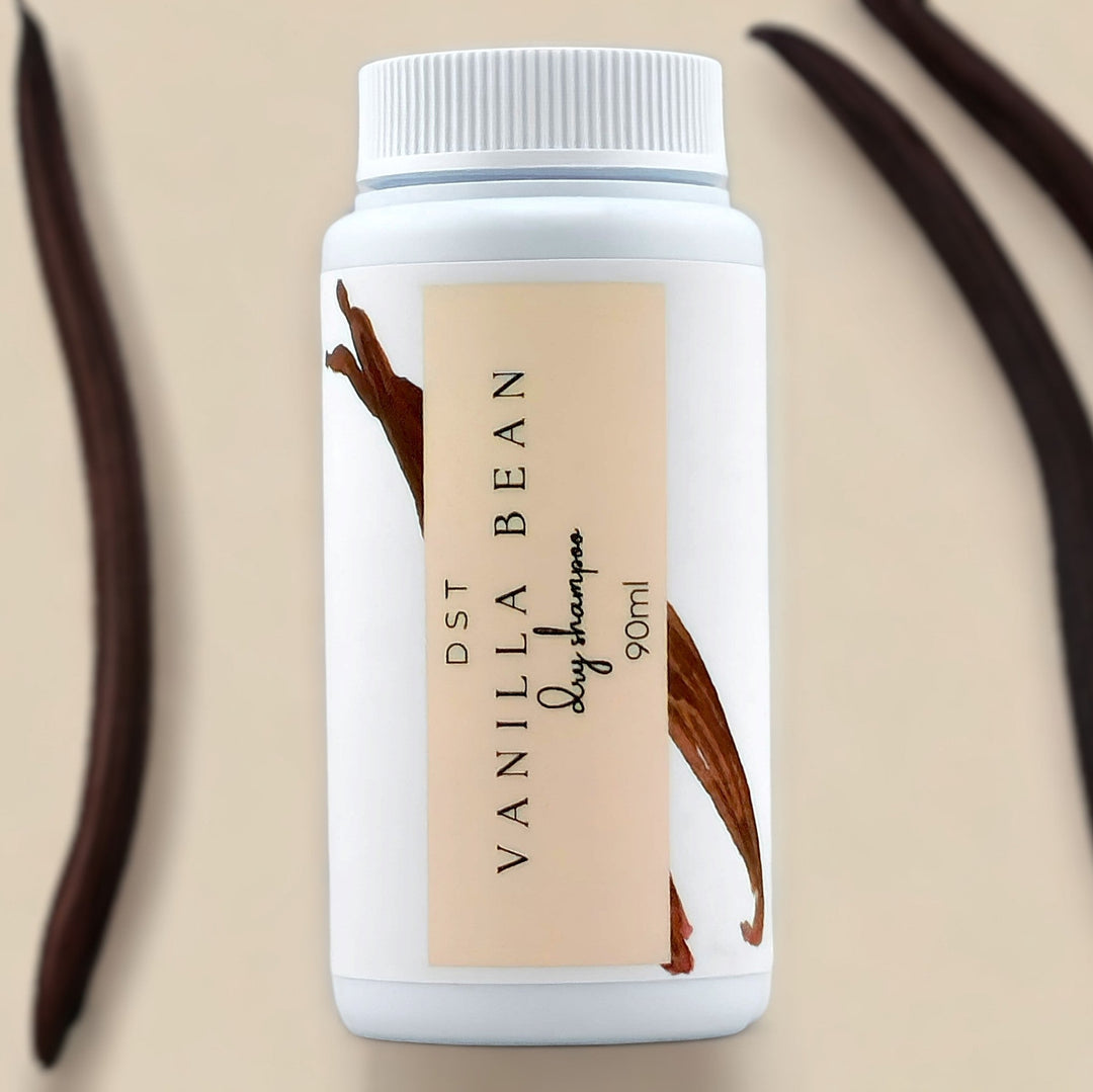 90ml bottle of Vanilla Bean scented Dry Shampoo powder against ivory background with long vanilla beans. 